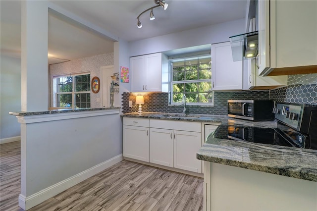 3910 14th Ave N, Saint Petersburg, FL 33713 - kitchen with stainless steel appliances, white cabinetry, light wood-style flooring, and tasteful backsplash