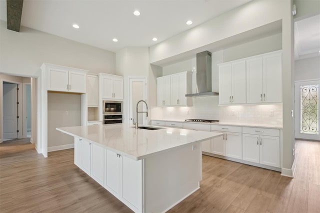 14531 Swiss Bridge Dr, Lithia, FL 33547 - kitchen with wall chimney range hood, appliances with stainless steel finishes, white cabinetry, a kitchen island with sink, and recessed lighting