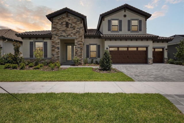 14531 Swiss Bridge Dr, Lithia, FL 33547 - mediterranean / spanish-style home with stucco siding, a tiled roof, decorative driveway, stone siding, and a garage