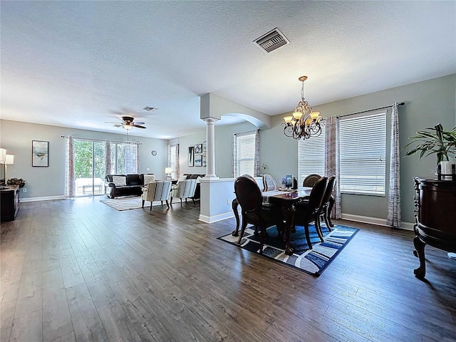 4116 Knollpoint Dr, Wesley Chapel, FL 33544 - dining room featuring decorative columns, a chandelier, dark wood-type flooring, arched walkways, and a textured ceiling
