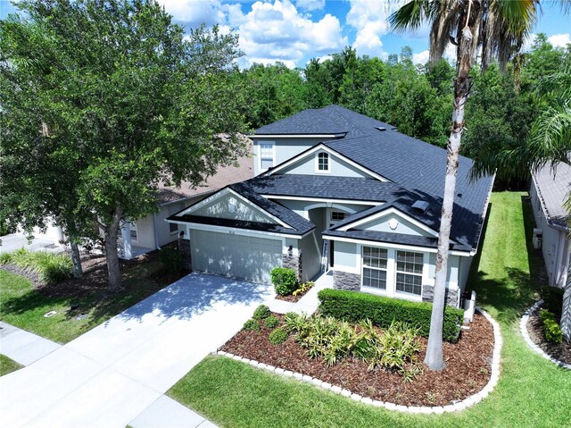 4116 Knollpoint Dr, Wesley Chapel, FL 33544 - view of front of property featuring a shingled roof, concrete driveway, stucco siding, a garage, and stone siding