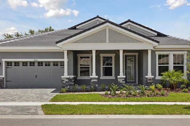 14523 Swiss Bridge Dr, Lithia, FL 33547 - craftsman inspired home with a garage, a porch, decorative driveway, a tiled roof, and stone siding