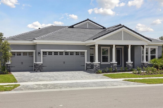 14523 Swiss Bridge Dr, Lithia, FL 33547 - craftsman inspired home featuring an attached garage, stone siding, stucco siding, decorative driveway, and covered porch