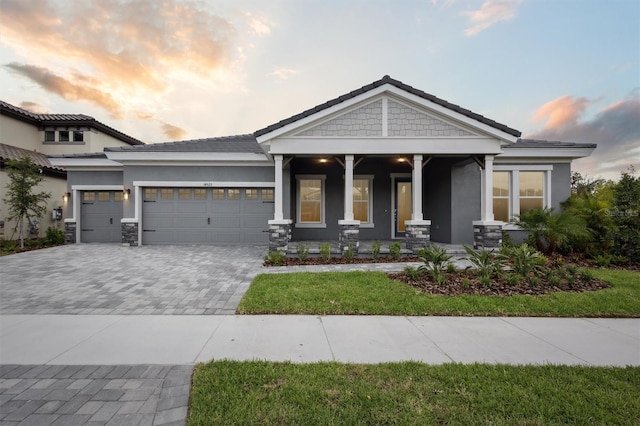 14523 Swiss Bridge Dr, Lithia, FL 33547 - view of front of house with covered porch, decorative driveway, stucco siding, and a garage
