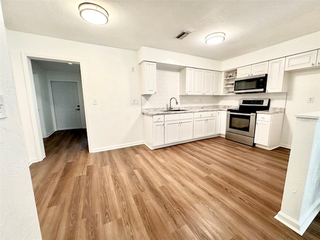 121 Granada Blvd, North Port, FL 34287 - kitchen featuring stainless steel appliances, open shelves, light countertops, light wood-style flooring, and white cabinets