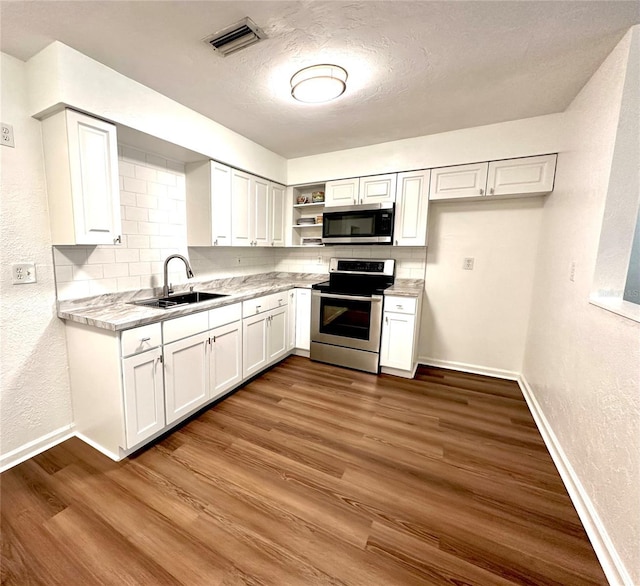 121 Granada Blvd, North Port, FL 34287 - kitchen featuring appliances with stainless steel finishes, open shelves, white cabinets, a textured wall, and backsplash