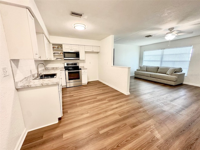 121 Granada Blvd, North Port, FL 34287 - kitchen with stainless steel appliances, open shelves, white cabinets, and light wood finished floors