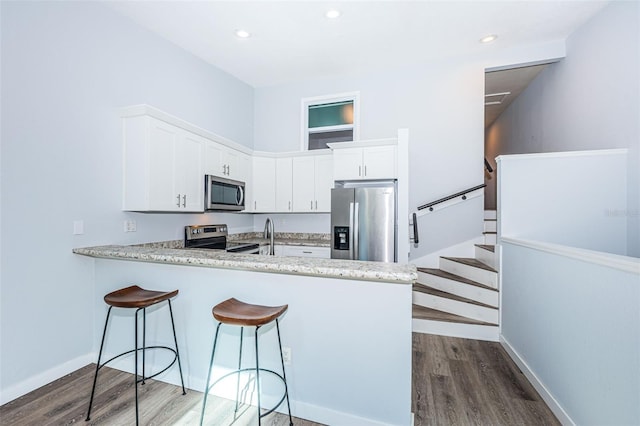 6206 92nd Pl N Unit 3605, Pinellas Park, FL 33782 - kitchen with stainless steel appliances, dark wood-style flooring, white cabinetry, a peninsula, and a breakfast bar