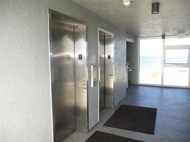 9980 Gulf Blvd Unit 408, Treasure Island, FL 33706 - hall with elevator, a textured wall, and tile patterned floors