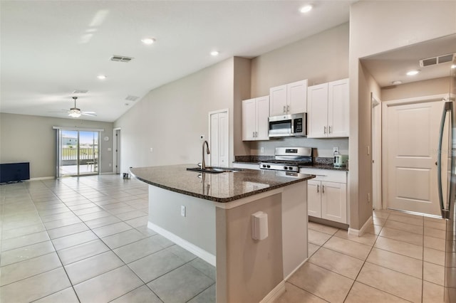 9437 Lemon Drop Loop, Sun City Center, FL 33573 - kitchen with appliances with stainless steel finishes, light tile patterned flooring, vaulted ceiling, an island with sink, and white cabinetry