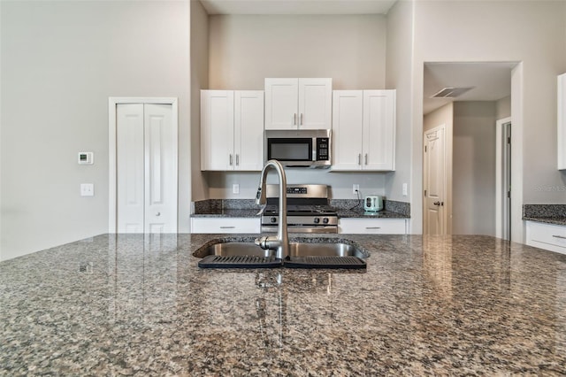 9437 Lemon Drop Loop, Sun City Center, FL 33573 - kitchen with appliances with stainless steel finishes, white cabinetry, and dark stone counters