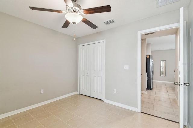 9437 Lemon Drop Loop, Sun City Center, FL 33573 - unfurnished bedroom with freestanding refrigerator, light tile patterned flooring, a closet, and a ceiling fan