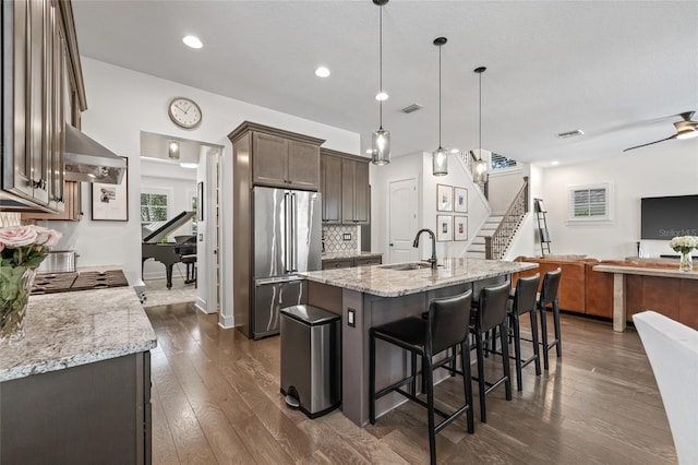 311 12th Ave N, Saint Petersburg, FL 33701 - kitchen with high quality fridge, wall chimney exhaust hood, light stone counters, a breakfast bar area, and dark wood-style flooring