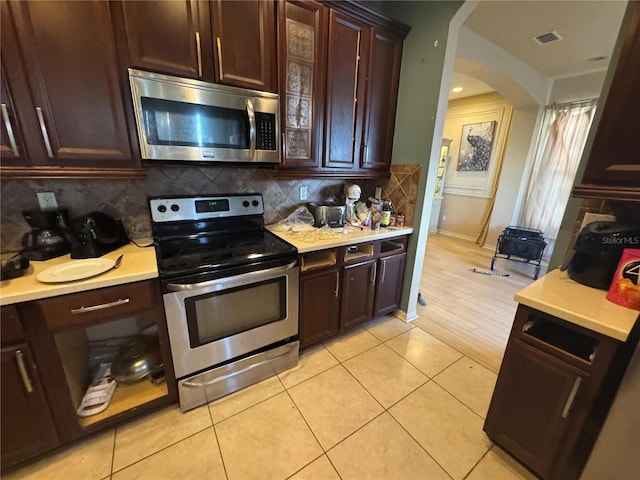 16027 Vine Cliff Ave, Hudson, FL 34667 - kitchen featuring appliances with stainless steel finishes, arched walkways, light countertops, and tasteful backsplash
