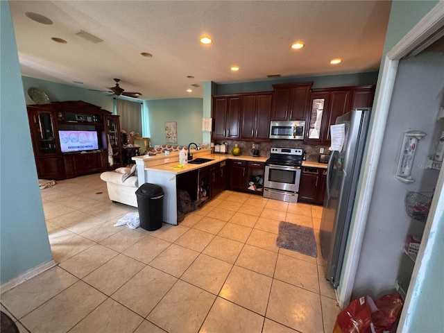 16027 Vine Cliff Ave, Hudson, FL 34667 - kitchen featuring appliances with stainless steel finishes, a peninsula, light countertops, tasteful backsplash, and light tile patterned flooring