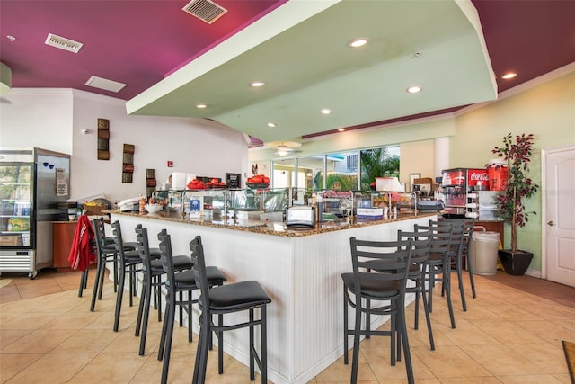 12000 Gulf Blvd Unit 403-S, Treasure Island, FL 33706 - kitchen with tile patterned flooring, crown molding, dark stone counters, recessed lighting, and a kitchen bar