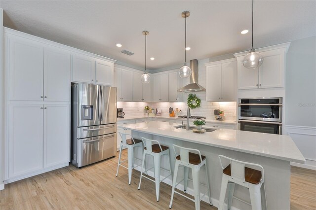 314 Blackrock Ln, Apollo Beach, FL 33572 - kitchen featuring appliances with stainless steel finishes, wall chimney range hood, tasteful backsplash, a breakfast bar, and white cabinets