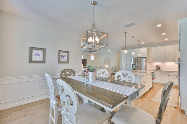 314 Blackrock Ln, Apollo Beach, FL 33572 - dining space with a chandelier, light wood-style floors, a wainscoted wall, and recessed lighting
