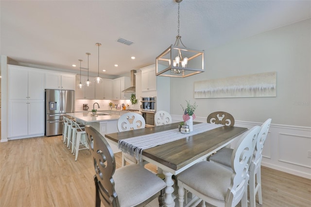 314 Blackrock Ln, Apollo Beach, FL 33572 - dining room featuring light wood-style flooring, a chandelier, wainscoting, a decorative wall, and recessed lighting