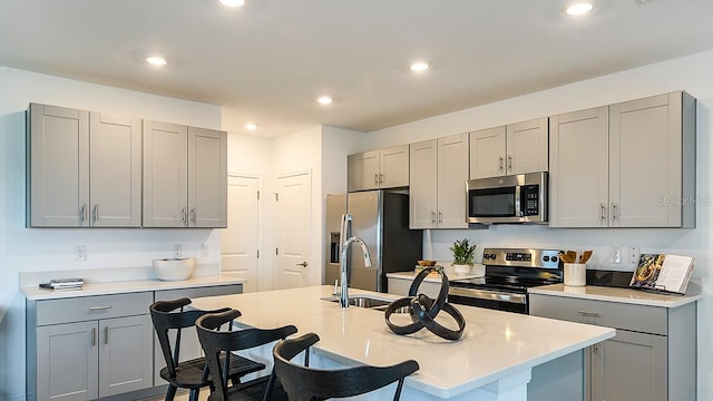 12474 Gust Ct, Hudson, FL 34669 - kitchen featuring stainless steel appliances, gray cabinetry, a breakfast bar, light countertops, and recessed lighting