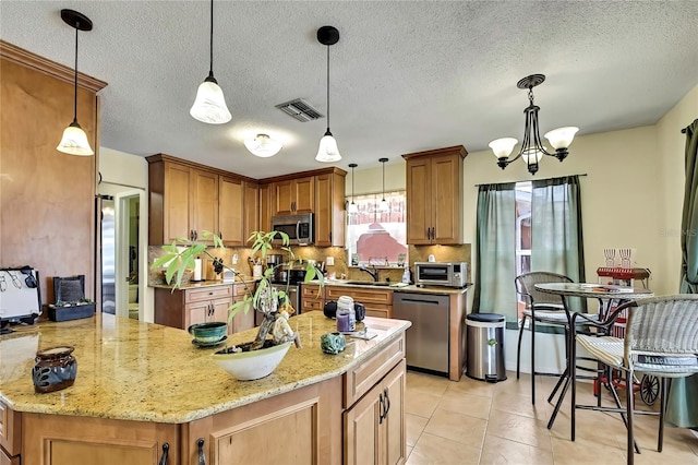 13814 Lavender Ave, Hudson, FL 34667 - kitchen featuring appliances with stainless steel finishes, decorative backsplash, light stone counters, a chandelier, and brown cabinets