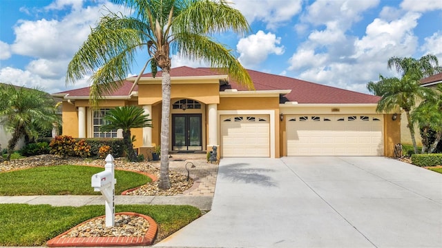 5309 Spectacular Bid Dr, Wesley Chapel, FL 33544 - view of front of house with an attached garage, stucco siding, concrete driveway, and french doors