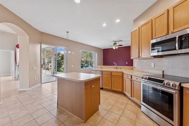 5309 Spectacular Bid Dr, Wesley Chapel, FL 33544 - kitchen with stainless steel appliances, ceiling fan, light tile patterned floors, light countertops, and a center island