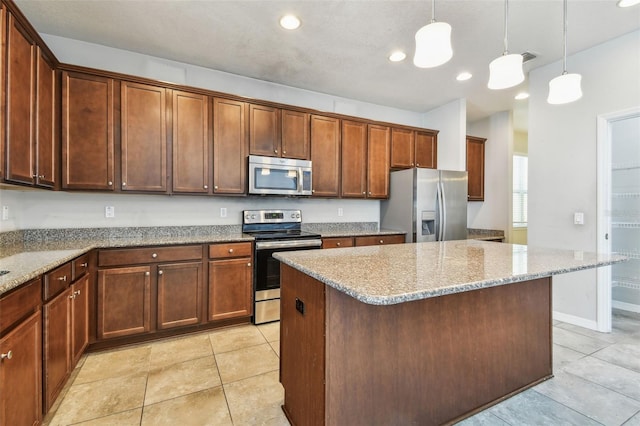 11541 Tangle Branch Ln, Gibsonton, FL 33534 - kitchen featuring appliances with stainless steel finishes, light stone counters, a center island, decorative light fixtures, and light tile patterned flooring