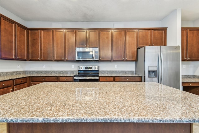 11541 Tangle Branch Ln, Gibsonton, FL 33534 - kitchen with appliances with stainless steel finishes, a kitchen island, and light stone counters