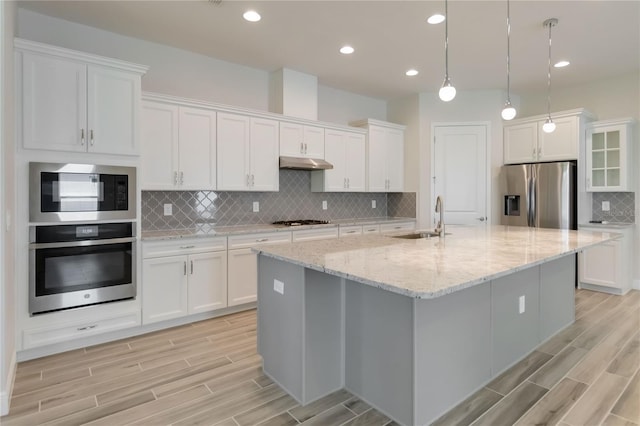 2132 Limestone Trl, Kissimmee, FL 34747 - kitchen with appliances with stainless steel finishes, wood tiled floors, under cabinet range hood, white cabinetry, and recessed lighting