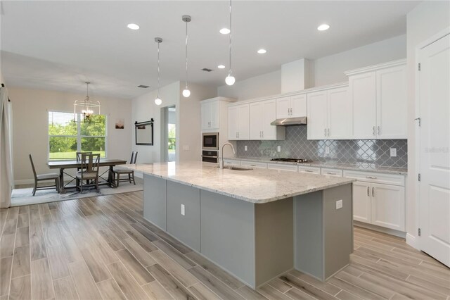 2132 Limestone Trl, Kissimmee, FL 34747 - kitchen with built in microwave, light wood-type flooring, white cabinets, tasteful backsplash, and recessed lighting