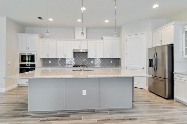 2132 Limestone Trl, Kissimmee, FL 34747 - kitchen featuring appliances with stainless steel finishes, under cabinet range hood, white cabinets, light wood-style floors, and recessed lighting