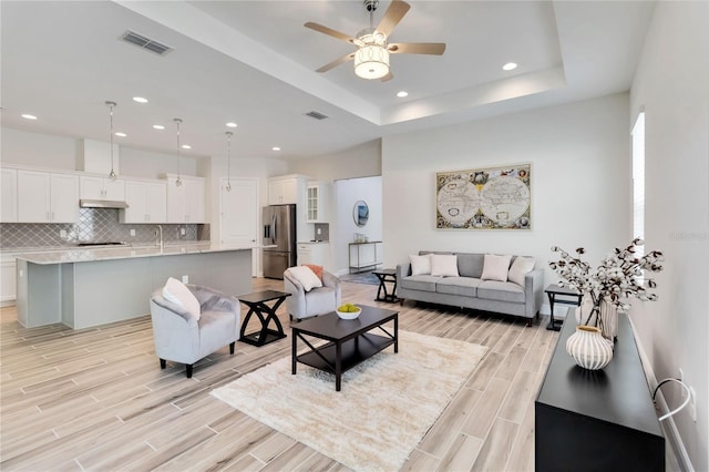 2132 Limestone Trl, Kissimmee, FL 34747 - living area featuring wood tiled floors, a ceiling fan, recessed lighting, and a raised ceiling