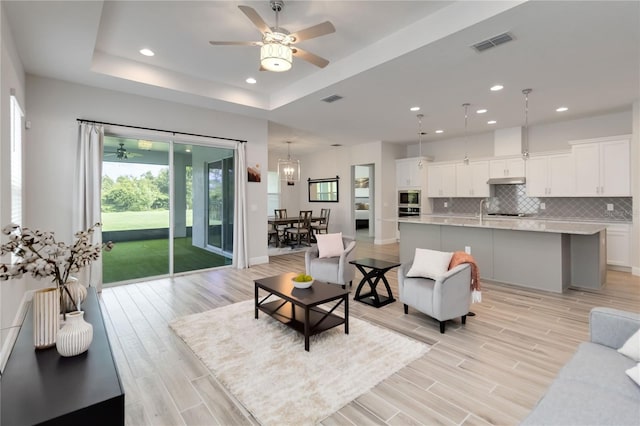 2132 Limestone Trl, Kissimmee, FL 34747 - living room featuring light wood-style floors, recessed lighting, ceiling fan, and a tray ceiling