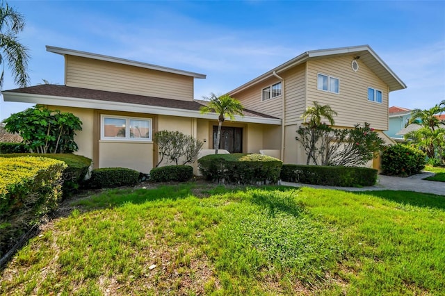 413 Midway Is, Clearwater Beach, FL 33767 - view of front of house with a front lawn, stucco siding, and roof with shingles