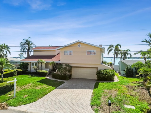 413 Midway Is, Clearwater Beach, FL 33767 - view of front of property featuring decorative driveway, an attached garage, a front lawn, and stucco siding