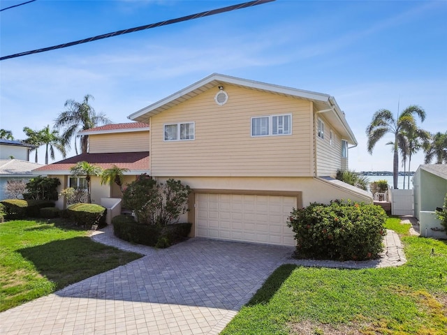 413 Midway Is, Clearwater Beach, FL 33767 - view of front of home featuring an attached garage, decorative driveway, stucco siding, and a front yard