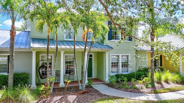 5518 Luminar Pointe Ln, Apollo Beach, FL 33572 - view of front of house featuring a standing seam roof, stucco siding, a porch, and a metal roof