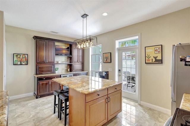 5518 Luminar Pointe Ln, Apollo Beach, FL 33572 - kitchen with freestanding refrigerator, light stone counters, open shelves, a center island, and pendant lighting