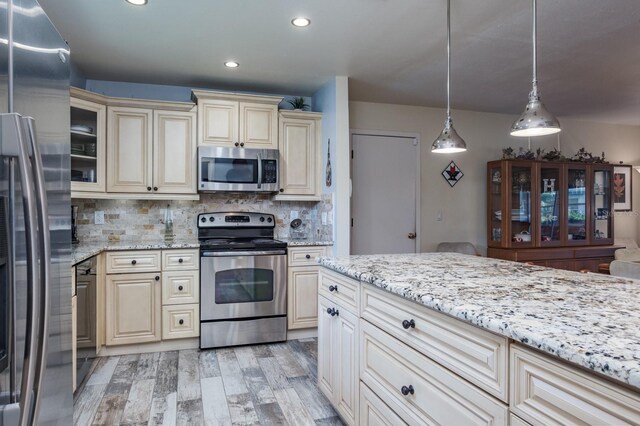 1510 Palmer Ct, Palm Harbor, FL 34685 - kitchen with appliances with stainless steel finishes, cream cabinets, light wood finished floors, light stone counters, and recessed lighting