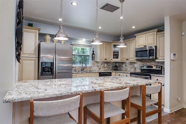 1510 Palmer Ct, Palm Harbor, FL 34685 - kitchen with cream cabinetry, appliances with stainless steel finishes, tasteful backsplash, a breakfast bar area, and wood finished floors