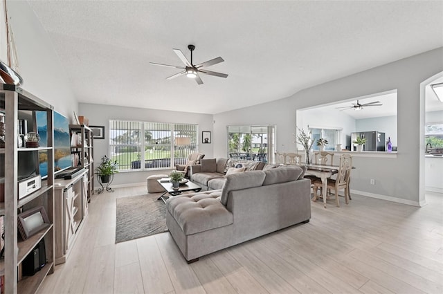 2306 Emerald Lake Dr, Sun City Center, FL 33573 - living room featuring ceiling fan, healthy amount of natural light, light wood-type flooring, lofted ceiling, and a textured ceiling