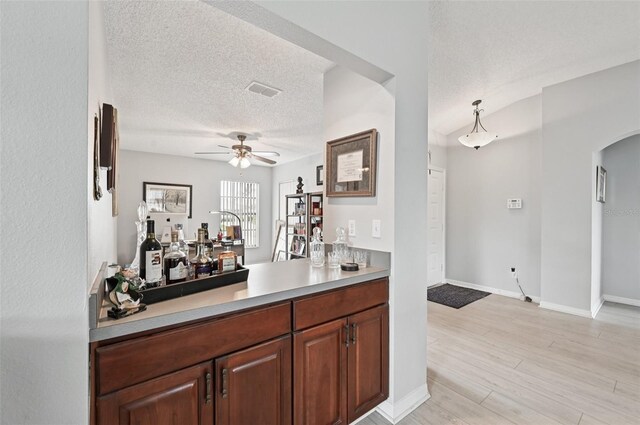 2306 Emerald Lake Dr, Sun City Center, FL 33573 - indoor dry bar with a ceiling fan, arched walkways, a textured ceiling, and light wood-style flooring