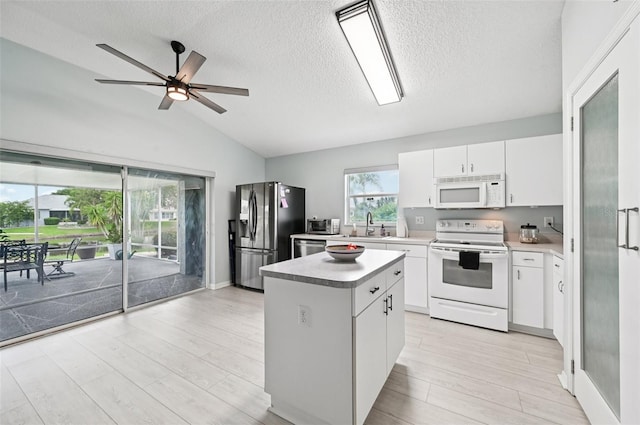 2306 Emerald Lake Dr, Sun City Center, FL 33573 - kitchen featuring appliances with stainless steel finishes, a textured ceiling, lofted ceiling, a kitchen island, and light countertops