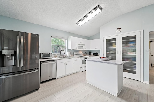 2306 Emerald Lake Dr, Sun City Center, FL 33573 - kitchen with stainless steel appliances, lofted ceiling, white cabinets, light countertops, and a textured ceiling