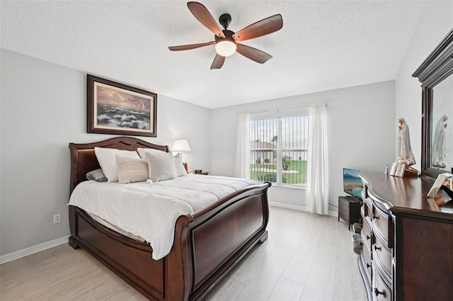 2306 Emerald Lake Dr, Sun City Center, FL 33573 - bedroom featuring a textured ceiling, light wood finished floors, and a ceiling fan