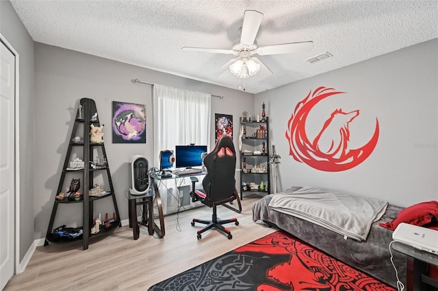 2306 Emerald Lake Dr, Sun City Center, FL 33573 - bedroom with wood finished floors, a desk, a textured ceiling, and a ceiling fan