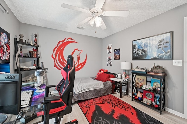 2306 Emerald Lake Dr, Sun City Center, FL 33573 - bedroom featuring wood finished floors, a textured ceiling, and a ceiling fan
