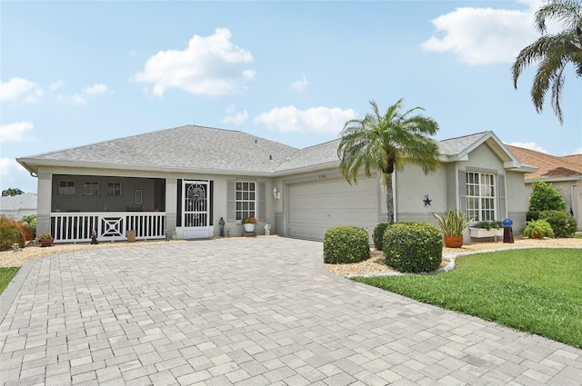 2306 Emerald Lake Dr, Sun City Center, FL 33573 - ranch-style house featuring decorative driveway, stucco siding, an attached garage, and a front yard