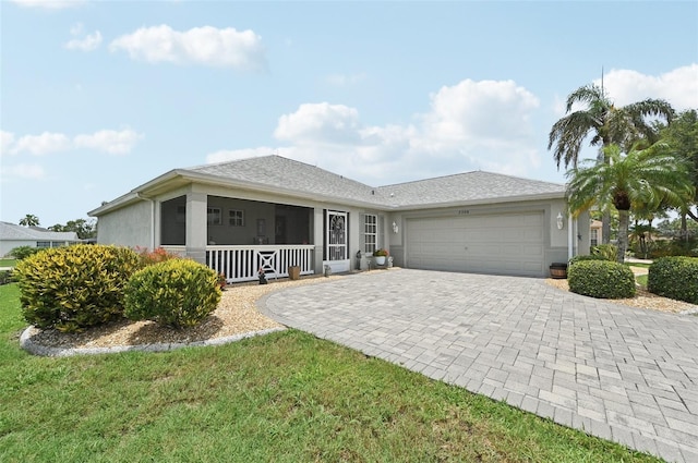 2306 Emerald Lake Dr, Sun City Center, FL 33573 - ranch-style home featuring an attached garage, decorative driveway, stucco siding, and covered porch